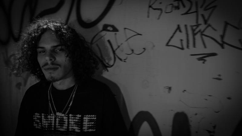 Black and white artist portrait against a graffiti wall
