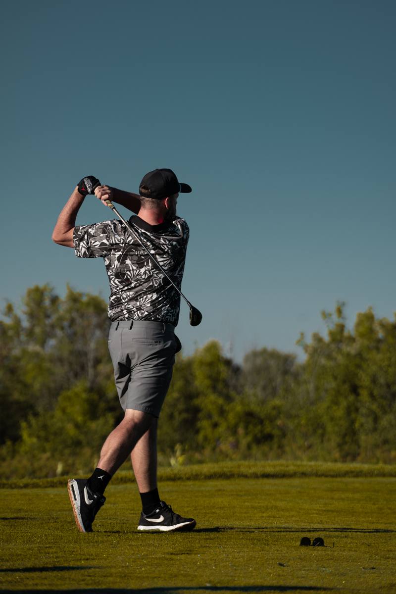 Golfer mid-swing at sunset during the Nomo Tour